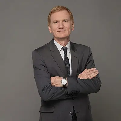 Ein Jurist mit verschränkten Armen vor einem grauen Hintergrund